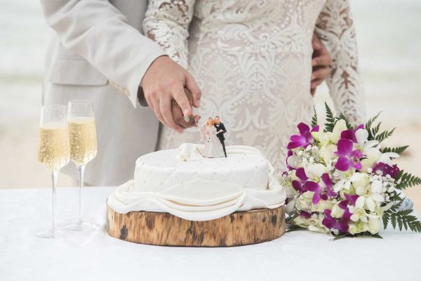 wedding cake on a wooden plate with champagne and bouquet