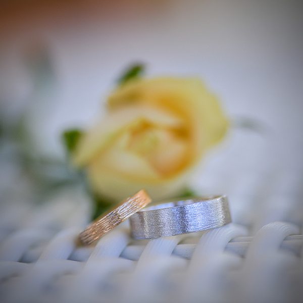 wedding rings and yellow flower in background