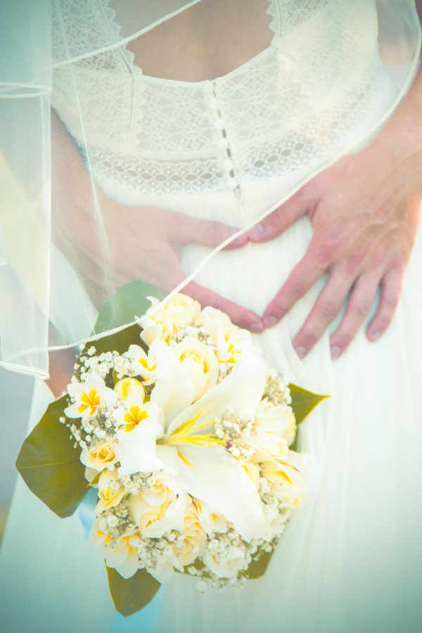 creative shot of groom forming a heart with hands with yellow flowers