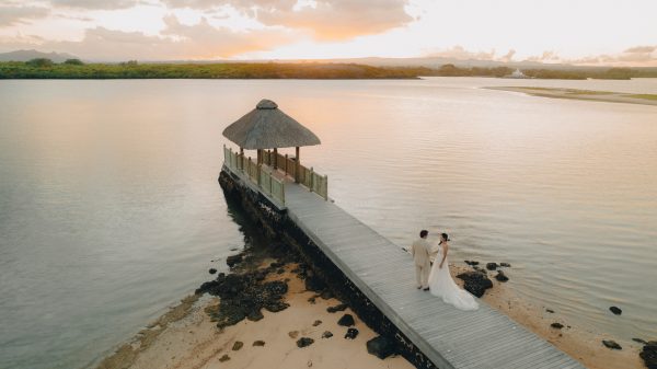 couple posing on the jetty with sunset background