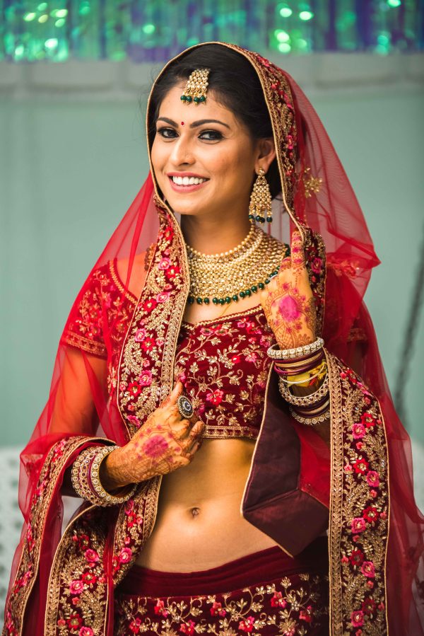 The bride in a red saree and smiling 