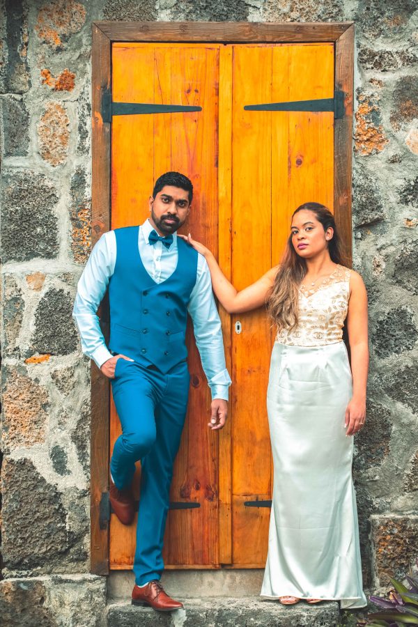 A couple is posing for a wedding photo shoot in front of yellow vintage door 