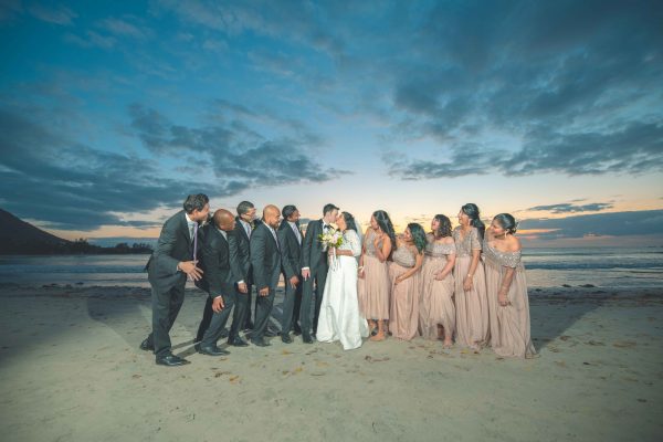 Group photo of the bride, her bridesmaids, the groom, and his groomsmen at the beach in Mauritius
